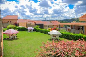 a yard with tables and umbrellas in the grass at Jatheo Hotel Rwentondo in Mbarara