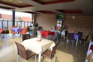 a restaurant with tables and chairs and a brick wall at Jatheo Hotel Rwentondo in Mbarara
