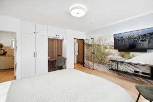 - une chambre blanche avec un grand lit et une télévision dans l'établissement Modernes Studio am Bremer Dom mit Balkon, à Brême