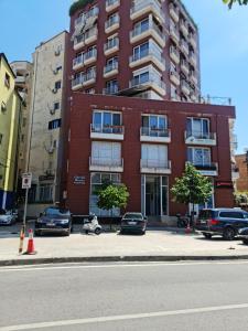 un bâtiment en briques rouges avec des voitures garées devant lui dans l'établissement 6th floor Apartments, Apartament Tirana, à Tirana