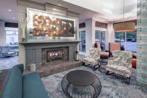 a living room with a fireplace and a couch and chairs at Hilton Garden Inn Sacramento/South Natomas in Sacramento