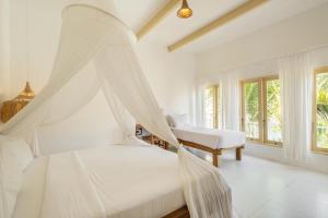 a bedroom with two beds with mosquito nets at The Warm Sun - Bingin in Uluwatu