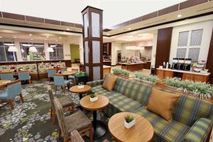 eine Hotellobby mit Sofas und Tischen sowie eine Cafeteria in der Unterkunft Hilton Garden Inn Covington/Mandeville in Covington