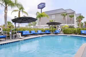 Hampton Inn Vero Beach Outlets في فيرو بيتش: مسبح مع كراسي ومظلات في الفندق