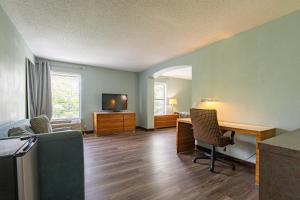 a living room with a bed and a desk and a television at Baymont by Wyndham Creedmoor in Creedmoor