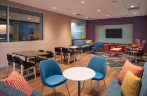 a waiting room with tables and chairs and a screen at Tru By Hilton Jacksonville South Mandarin, Fl in Jacksonville