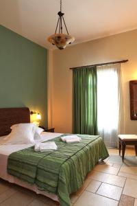 ein Schlafzimmer mit einem Bett mit einer grünen Decke und einem Fenster in der Unterkunft Xenonas Afroditi in Loutra