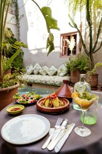 Riad 117 في مراكش: طاولة مع أطباق من الطعام وكأس من النبيذ