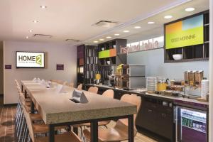 蔓越莓乡Home2Suites Pittsburgh Cranberry的有一张长桌子和椅子的餐厅