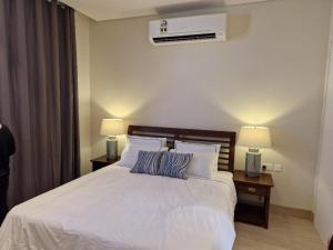 1 dormitorio con 1 cama blanca grande y 2 lámparas en Glory Villa 05 en Salalah