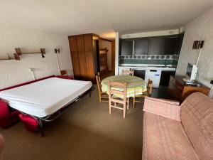 a room with a bed and a table and a kitchen at Monolocale Alberti Rainalter in Madonna di Campiglio