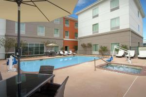 a pool with chairs and an umbrella next to a building at Hilton Garden Inn Odessa in Odessa
