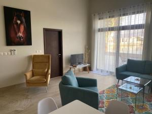 Sala de estar con 2 sillas azules y TV en Glory Villa 05 en Salalah