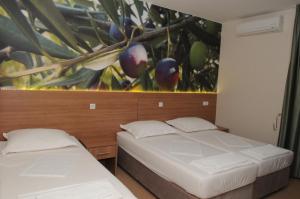 two beds in a room with a painting on the wall at Guest House Ostojić in Međugorje