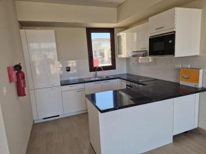 cocina con armarios blancos y encimera negra en Glory Villa 05 en Salalah