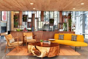 a living room with a yellow couch and chairs at Canopy By Hilton Tempe Downtown in Tempe