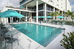 una piscina con sillas y sombrillas frente a un edificio en DoubleTree by Hilton Miami Doral, en Miami