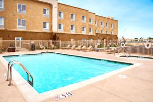 a swimming pool with chairs and a building at Hampton Inn & Suites Ridgecrest in Ridgecrest