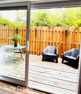 eine Terrasse mit Stühlen, einem Tisch und einem Zaun in der Unterkunft Faranel in Berlaimont