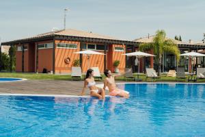 Dos mujeres están sentadas en una piscina en Hello Villas, en Carvoeiro