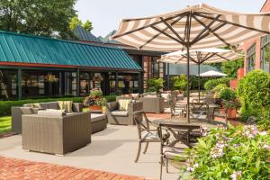 an outdoor patio with tables and chairs and umbrellas at The Saratoga Hilton in Saratoga Springs