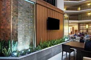 a restaurant with a tv on a wall with plants at Embassy Suites by Hilton Portland Tigard in Tigard