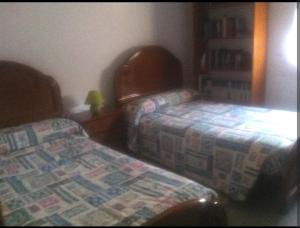 1 dormitorio con 2 camas y estante para libros en Casa dala, en aguiño, en Ribeira