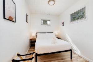 a white bedroom with a bed and a chair at Lovely Landing Pad near Lambert Airport 3 bed bath in Berkeley
