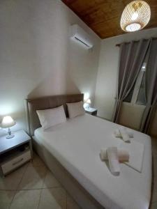 a bedroom with a white bed with two towels on it at GKOROS HOUSE OLD TOWN in Himare