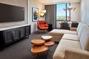 sala de estar con sofá y TV de pantalla plana en Senna House Hotel Scottsdale, Curio Collection By Hilton, en Scottsdale