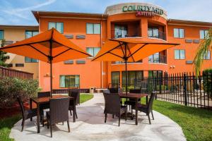 a table and chairs with umbrellas in front of a building at Courtyard by Marriott Corpus Christi in Corpus Christi