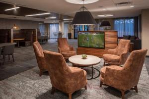 a lobby with a tv and chairs and a table at Courtyard Cincinnati Airport South/Florence in Florence