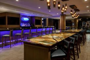 a bar in a restaurant with purple lighting at Hilton Charlotte University Place in Charlotte