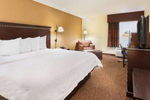 a hotel room with a large bed and a chair at Hampton Inn Charlotte University Place in Charlotte