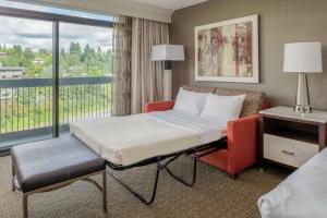 a bed and a chair in a room with a window at Hilton Bellevue in Bellevue