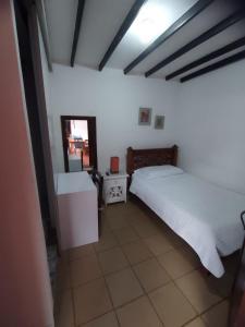 a bedroom with a white bed and a mirror at Hotel Colonial Andino - Parque principal de Pitalito in Pitalito