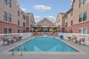 a swimming pool in a courtyard with chairs and a building at Homewood Suites by Hilton Houston-Clear Lake in Webster