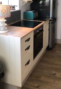 a kitchen with white cabinets and a stove top oven at Dinky cottage in Brightlingsea