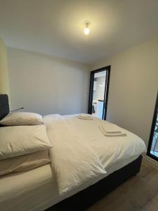 una camera da letto con due letti con lenzuola bianche e una finestra di Le Paris Plage a Le Touquet-Paris-Plage