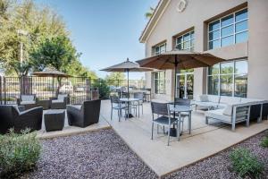 un patio avec des chaises, des tables et des parasols dans l'établissement Homewood Suites Phoenix-Metro Center, à Phoenix