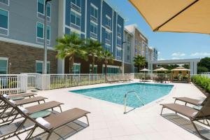 a swimming pool with chaise lounge chairs and a resort at Hilton Garden Inn Apopka City Center, Fl in Orlando