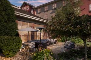 un patio del hotel con mesas, sillas y una sombrilla en Hilton Garden Inn Rockford, en Rockford