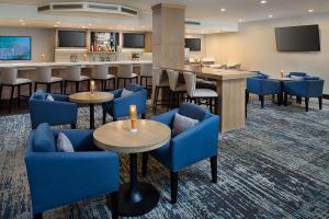 a lobby with blue chairs and tables and a bar at Hilton Atlanta Perimeter Suites in Atlanta