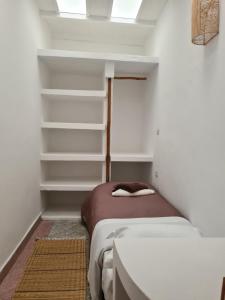 a small bedroom with a bed and shelves at La Maison des Vagues in Sidi Kaouki