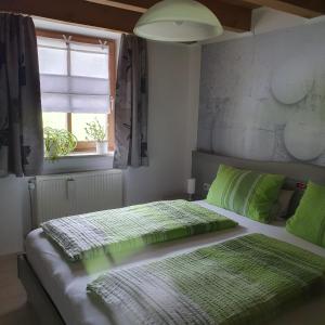 1 dormitorio con 2 camas con sábanas verdes y ventana en Haus Sonntal, en Bodenmais