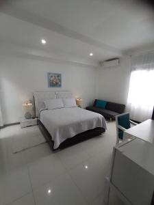 um quarto branco com uma cama grande e um sofá em Hotel Colonial Andino - Parque principal de Pitalito em Pitalito