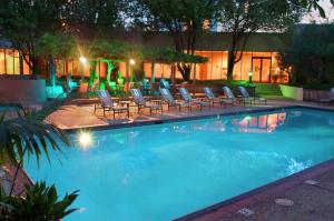 a large swimming pool with lounge chairs and lights at Hilton Houston Westchase in Houston