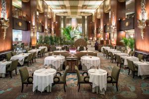 uma sala de jantar com mesas e cadeiras brancas em Hilton Cincinnati Netherland Plaza em Cincinnati