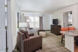 Habitación de hotel con sofá, sillas y TV en Homewood Suites by Hilton Raleigh/Crabtree Valley, en Raleigh