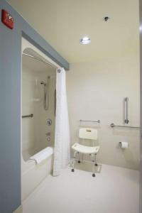 uma casa de banho com um chuveiro e uma cadeira. em DoubleTree by Hilton Binghamton em Binghamton
